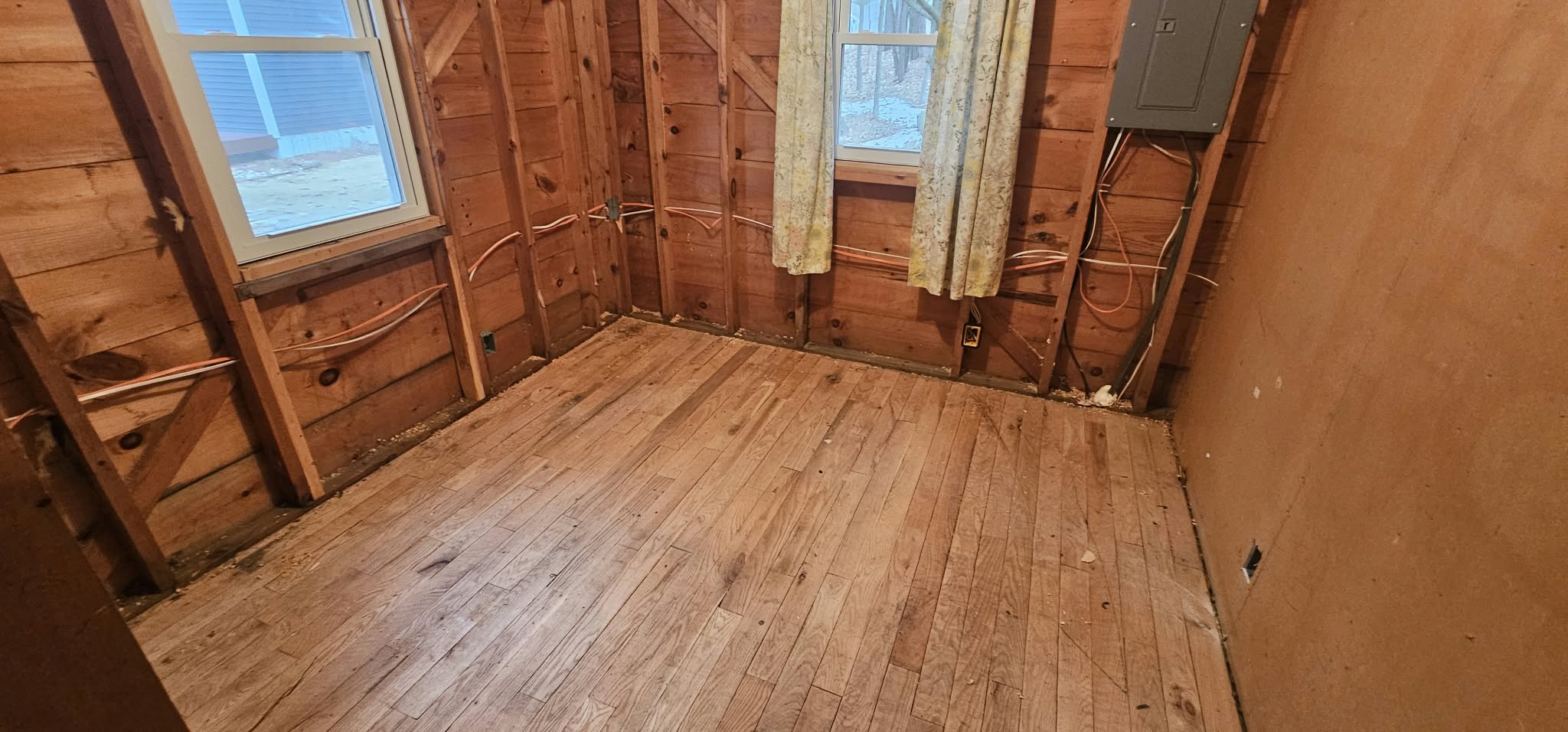 Before — bare framing, exposed copper plumbing, original hardwood