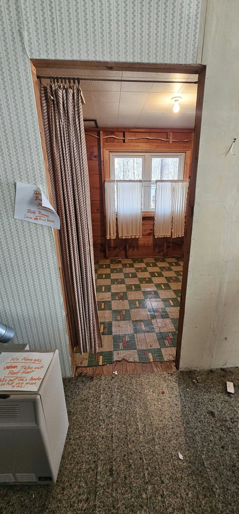 Before — original cabin interior, old wallpaper and linoleum floor