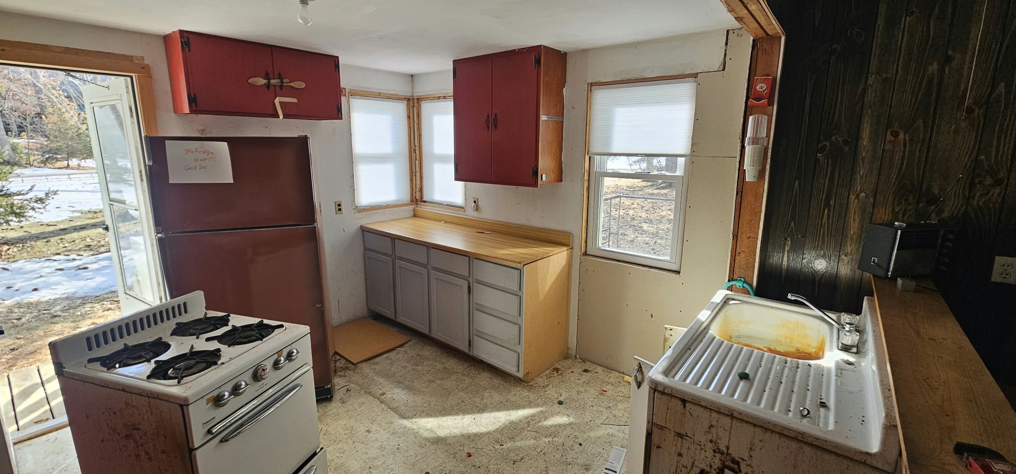Before — kitchen with original red cabinets, rusted sink and old gas stove