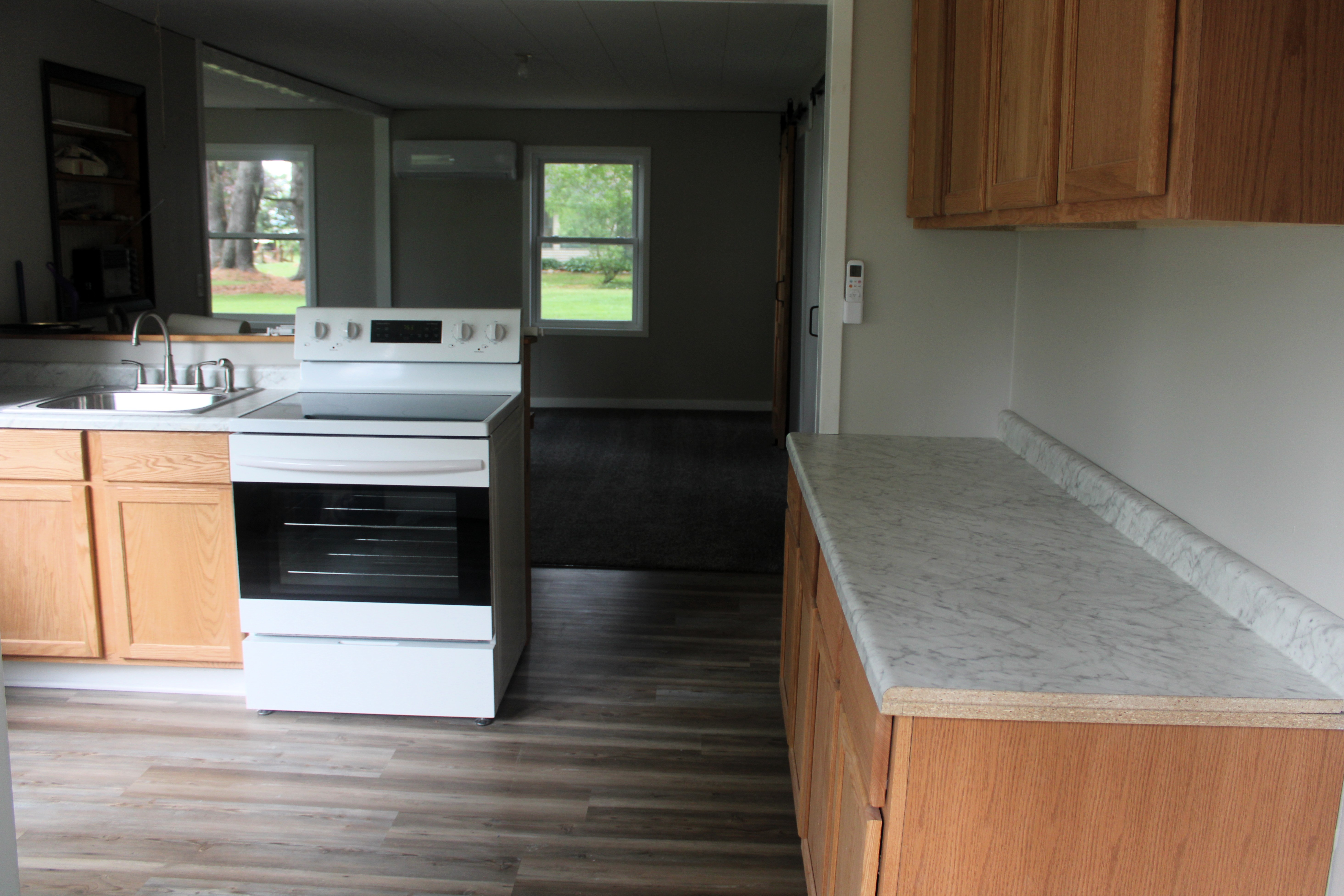 After — kitchen with LVP flooring, white appliances, barn doors visible